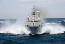 USS Milwaukee (LCS-5) sets sail in open waters. It sprays ocean water mist from its sides as it moves forward.