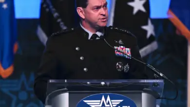 US Chief of Space Operations Gen. B. Chance Saltzman is seen standing on a podium, seemingly mid-speech. Four military flags are seen behind him.