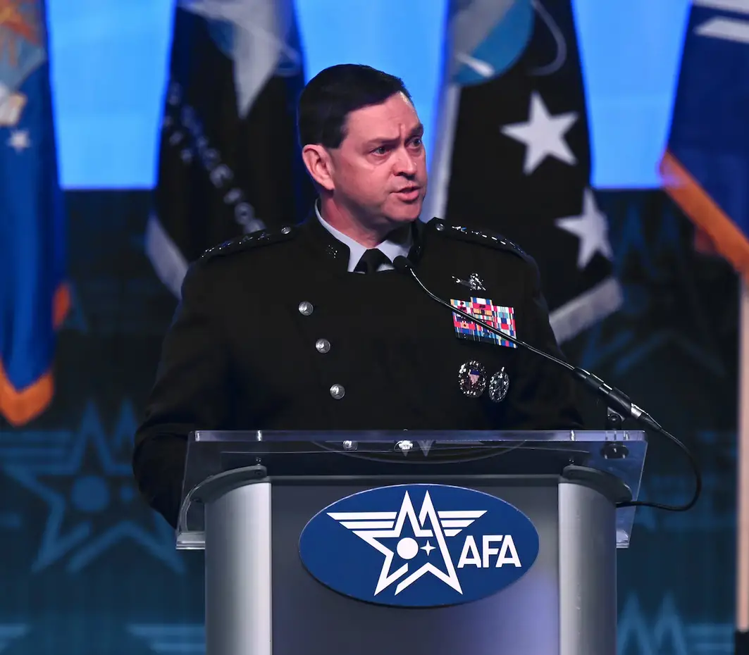 US Chief of Space Operations Gen. B. Chance Saltzman is seen standing on a podium, seemingly mid-speech. Four military flags are seen behind him.