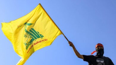 A masked demonstrator waves a flag of the Iran-backed Lebanese Shiite movement Hezbollah