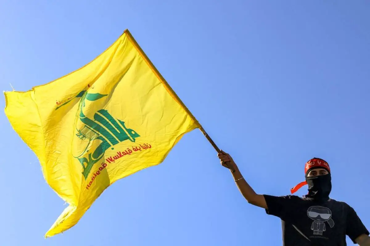 A masked demonstrator waves a flag of the Iran-backed Lebanese Shiite movement Hezbollah
