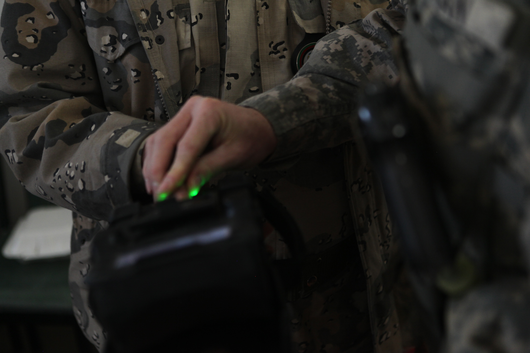 An Army soldier demonstrates a biometrics device during Vice Adm. Robert S. Harward's visit to Zaranj, Afghanistan, Jan 6. The commanding officer of Combined Joint Interagency Task Force 435 toured a provincial prison and the Iran/Afghanistan border crossing.