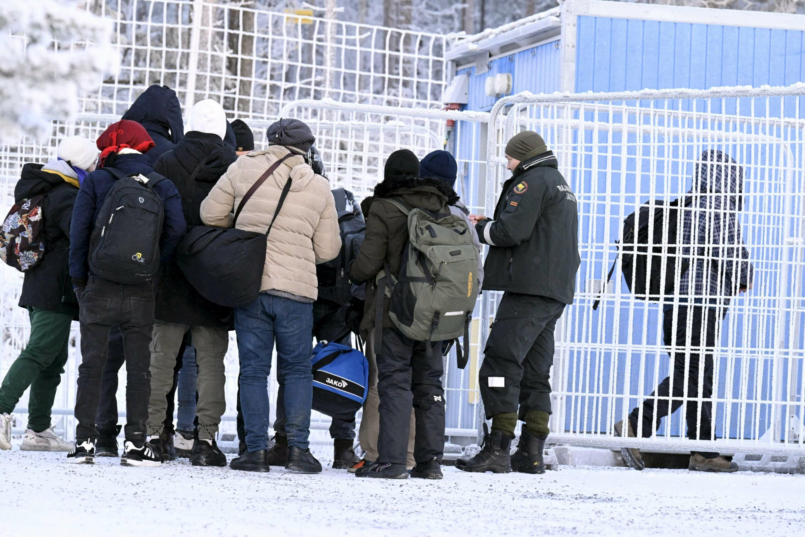 Finnish Border Guards check the documents of arriving migrants at the international border crossing at Salla, northern Finland