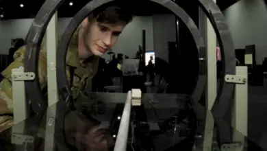 A uniformed personnel peeks inside a quantum tech display in a technology convention.