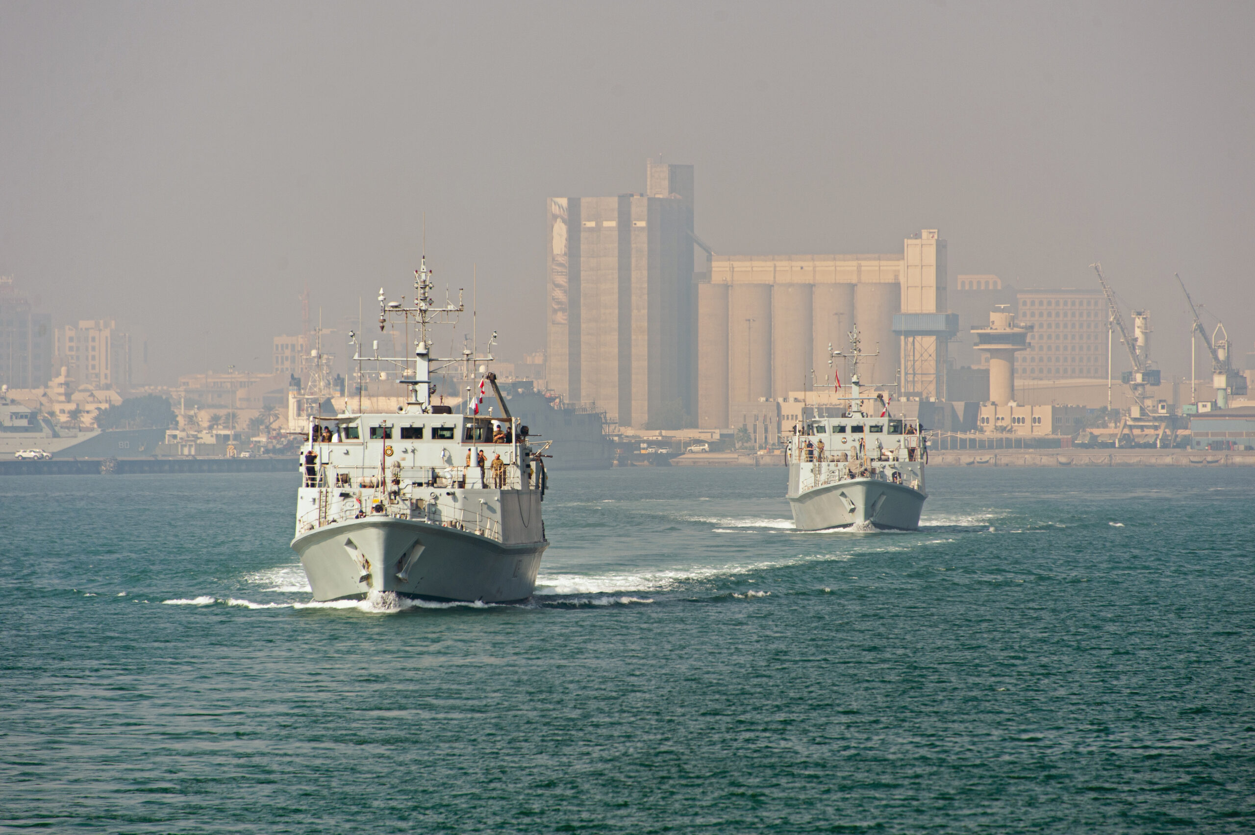 HMS Penzance leads HMS Shoreham out of Mina Salman Port in Bahrain whilst deployed on Op KIPION. The ships are both Sandown Class minehunters, each crewed by a dedicated team of 41. From specially trained divers to remote mine disposal system experts, this courageous unit detects and destroys hidden dangers all over the globe.