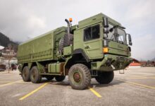 A Rheinmetall military truck is seen in parked in a lot. The truck is painted camouflage green.