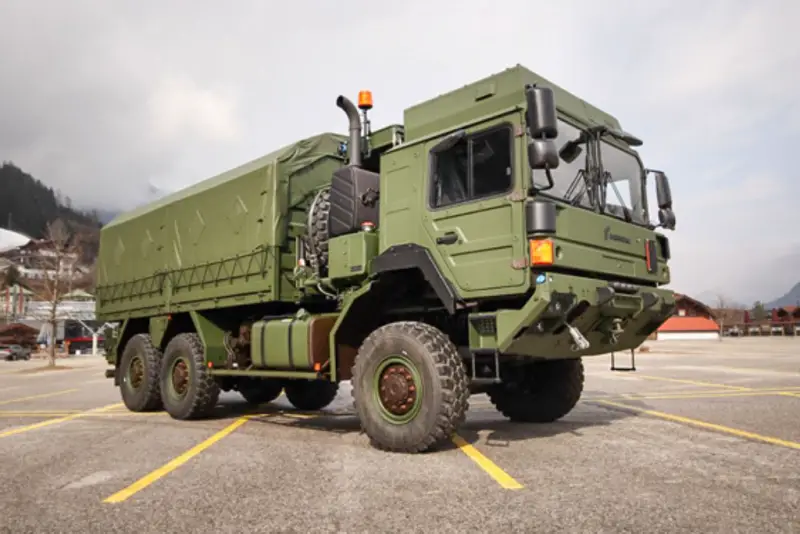 A Rheinmetall military truck is seen in parked in a lot. The truck is painted camouflage green.