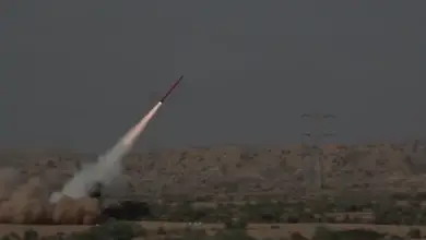 A Fatah-II missile is launched in a plains. It's seen blasting off to the northeast. The plains have green bushes scattered across its yellow sands.