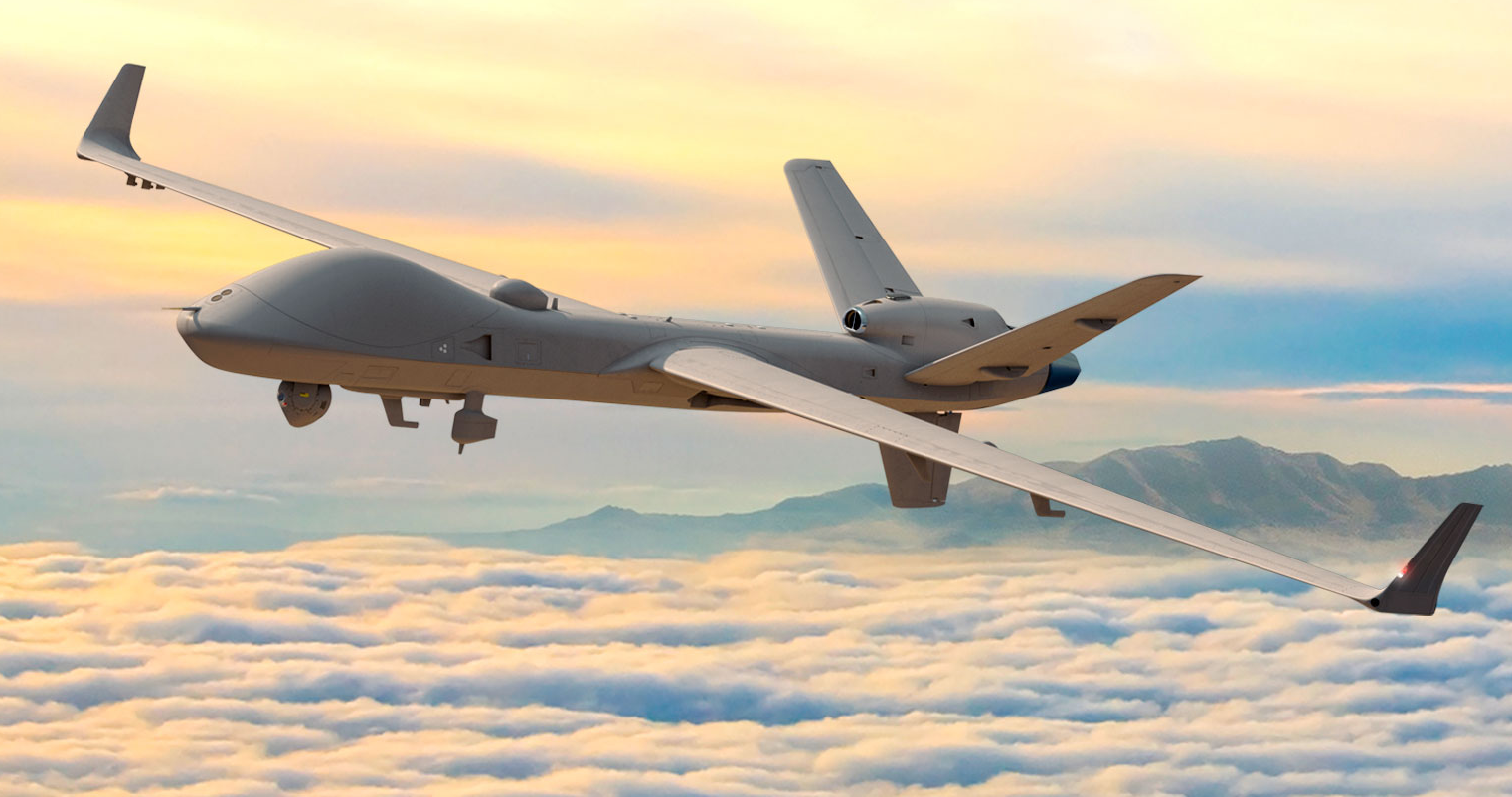 A gray General Atomics MQ-9B SkyGuardian is seen flying above the clouds. On the far right side of the background, a mountain range is seen peeking out. The scenery is tinged in the setting sun's orange hues.