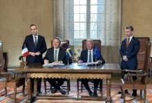 MBDA CEO Éric Béranger and Saab CEO Micael Johansson are seen signing a letter of intent on a table decorated with France, Sweden, and the EU's flags. On the left, they are witnessed by French Minister for the Armed Forces Sébastien Lecornu, and on the right, Swedish Minister for Defence Pål Jonson.
