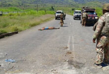 This handout picture released by the Royal Papua New Guinea Constabulary on February 19, 2024 shows a dead body on a road as officials patrol near the town of Wabag