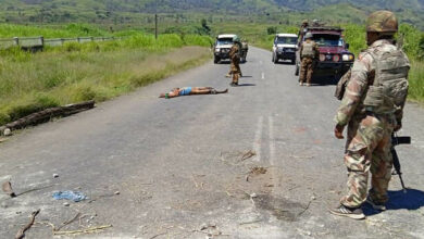 This handout picture released by the Royal Papua New Guinea Constabulary on February 19, 2024 shows a dead body on a road as officials patrol near the town of Wabag