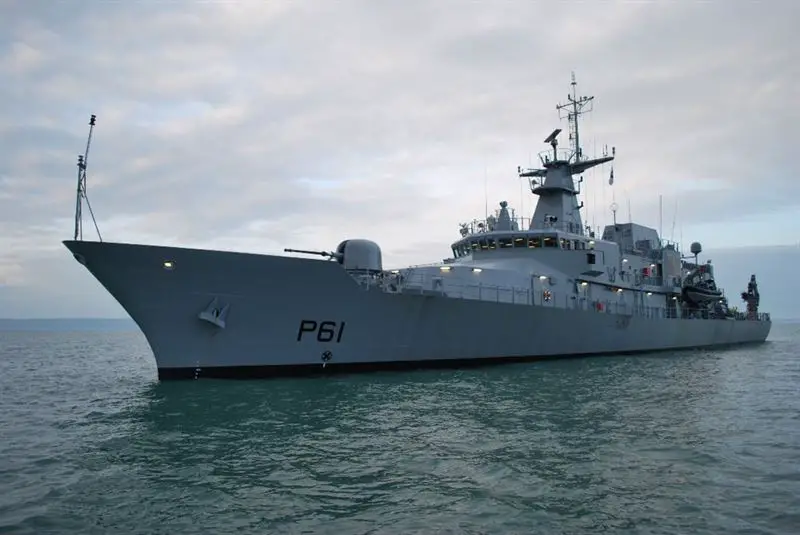 An Irish Naval Service's offshore patrol vehicle, LÉ Samuel Beckett (P61), is seen sailing calm, green-blue waters. The gray ship has "P61" painted on its hull in black. The sky in the background is cloudy and slightly overcast.