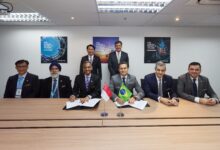 Eight officials from Embraer and ST Technologies are seen in a photo op as two of them sign the documents of the memorandum of agreement.