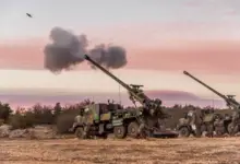 A Nexter CAESAR self-propelled howitzer is seen firing a 155mm artillery shell. The howitzer system is installed in the back of a 6x6 truck body.