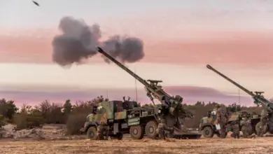 A Nexter CAESAR self-propelled howitzer is seen firing a 155mm artillery shell. The howitzer system is installed in the back of a 6x6 truck body.