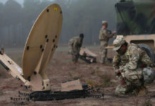 Soldier setting up a SATCOM dish on the field