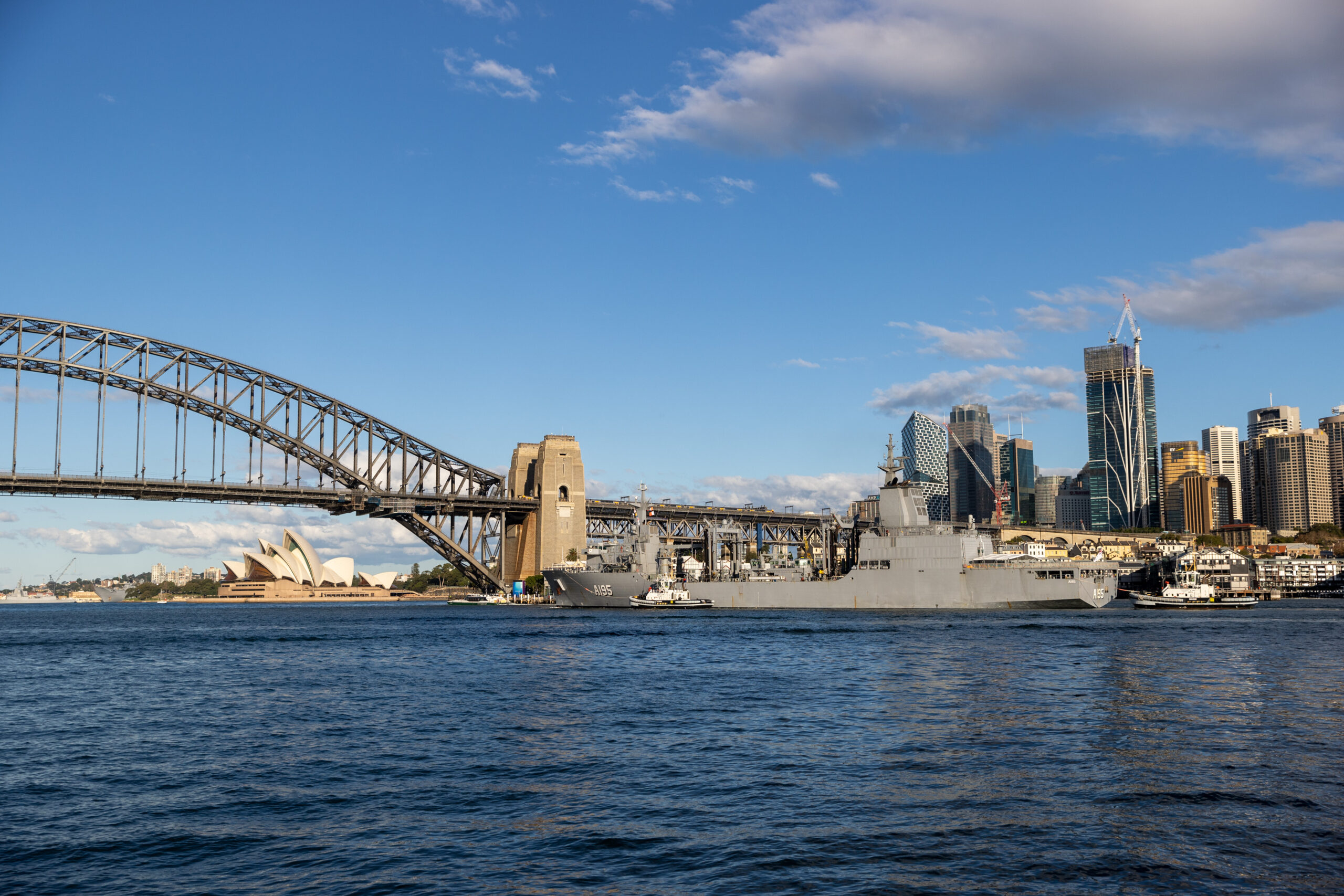 Royal Australian Navy replenishment ship HMAS Supply sails through Sydney Harbour after taking on fuel from the commercial fuel depot at Gore Cove. *** Local Caption *** Royal Australian Navy replenishment ship HMAS Supply completed another first since commissioning after passing under Sydney Harbour Bridge on Wednesday, 18 May 2022. HMAS Supply took on fuel from the commercial fuel depot at Gore Cove on the western side of Sydney Harbour Bridge ahead of departing Fleet Base East as part of a regional presence deployment en route to Exercise Rim of the Pacific (RIMPAC) in Hawaii. This was another first for the Supply-class oiler replenishment ships -- HMAS Supply and HMAS Stalwart -- as they continue to expand their operating capability. HMAS Supply was commissioned on 10 April 2021 and the second ship, HMAS Stalwart, was commissioned seven months later on 13 November 2021. The double-hulled ships carry fuel, dry cargo, water, food, ammunition, equipment and spare parts to provide operational support for deployed Navy ships and to support Australian Defence Force operations far from the port. HMAS Supply has already provided vital support to Operation Tonga Assist 2022.