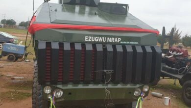 An Ezugwu Mine-Resistant Ambush Protected vehicle is seen parked. The armored vehicle is painted green, with the words "EZUGWU MRAP" painted in white in front.