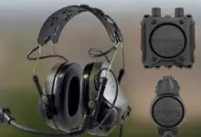 An image of an intercom system. The capability includes a headset with a microphone attached to it, and two items that appear to be receivers. The equipment are painted dark green and gray.