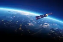 Artist's impression of a satellite in outer space. The satellite looms above the earth.