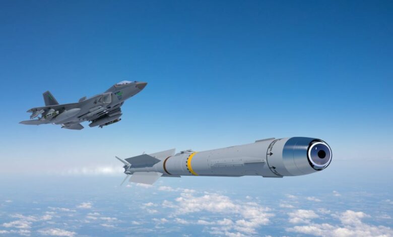 An artist's rendition of a KF-21 Boramae fighter jet flying above the clouds and firing off an IRIS-T missile. The jet plane, seen on the far left side of the image, is painted gray. The missile has a similar color scheme, seen jutting out white flames from its back as it propels itself forward. The background is a blue sky with white light clouds seen below.