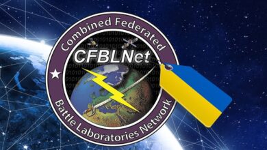 The logo of the Combined Federated Battle Laboratories Network with a tag with the Ukrainian flag's colors attached to it. The logo has a violet rim, with a globe in the middle of the layout with two satellites hovering above it. A sword and yellow lightning symbol is laid out on an X pattern over it. The upper middle part of the logo has the acronym "CFBLNet" written in a big white font.