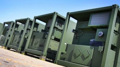Marshall's Deployable Operations and Maintenance System (DOMS) are seen lined up on a flat surface area. The DOMS appear to be box-shaped containers painted in green.