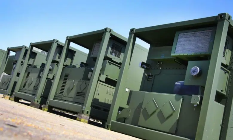 Marshall's Deployable Operations and Maintenance System (DOMS) are seen lined up on a flat surface area. The DOMS appear to be box-shaped containers painted in green.